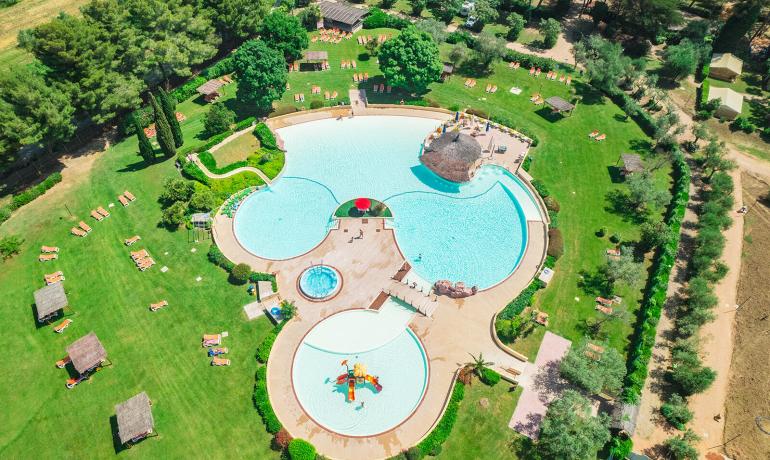 Vue aérienne d'une piscine avec jardin et transats.