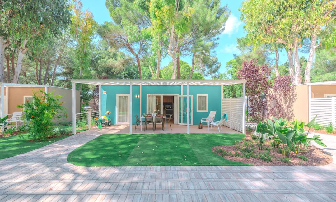 Nowoczesny bungalow z patio, otoczony drzewami i zielonym ogrodem.