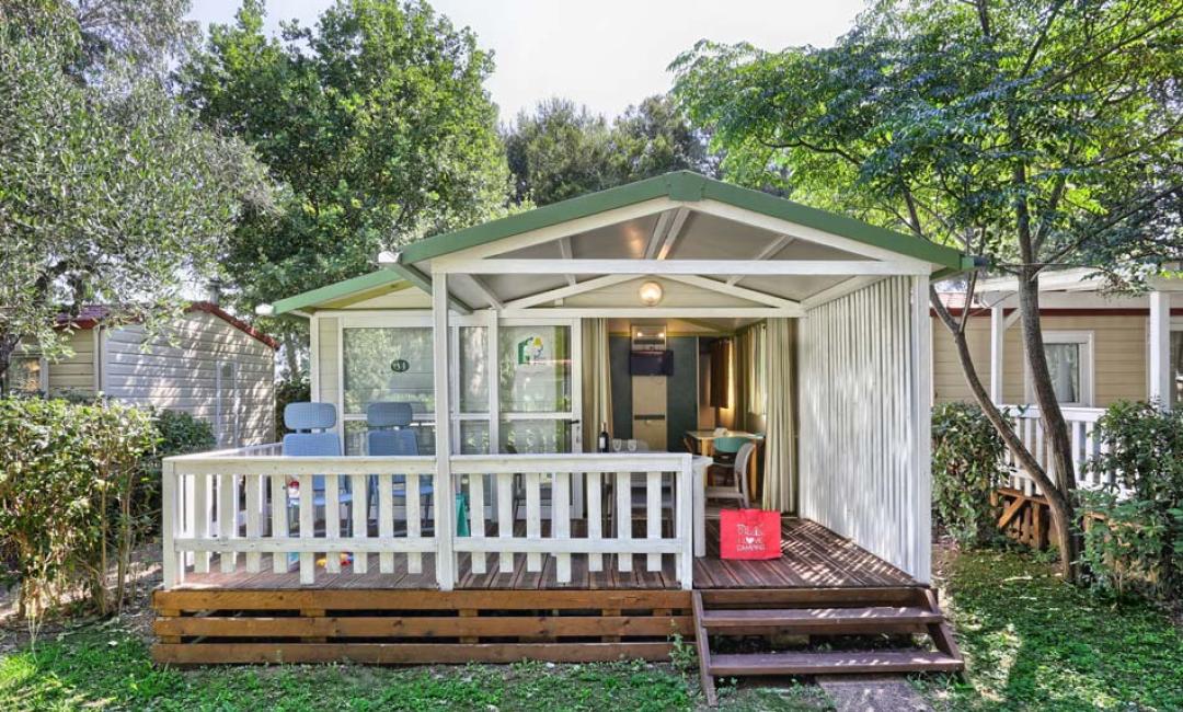 Bungalow met veranda, omringd door bomen, perfect voor een ontspannen vakantie.