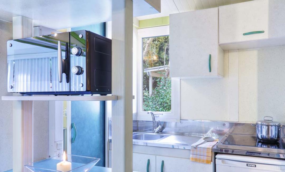 Heldere moderne keuken met raam, magnetron en kookplaat.