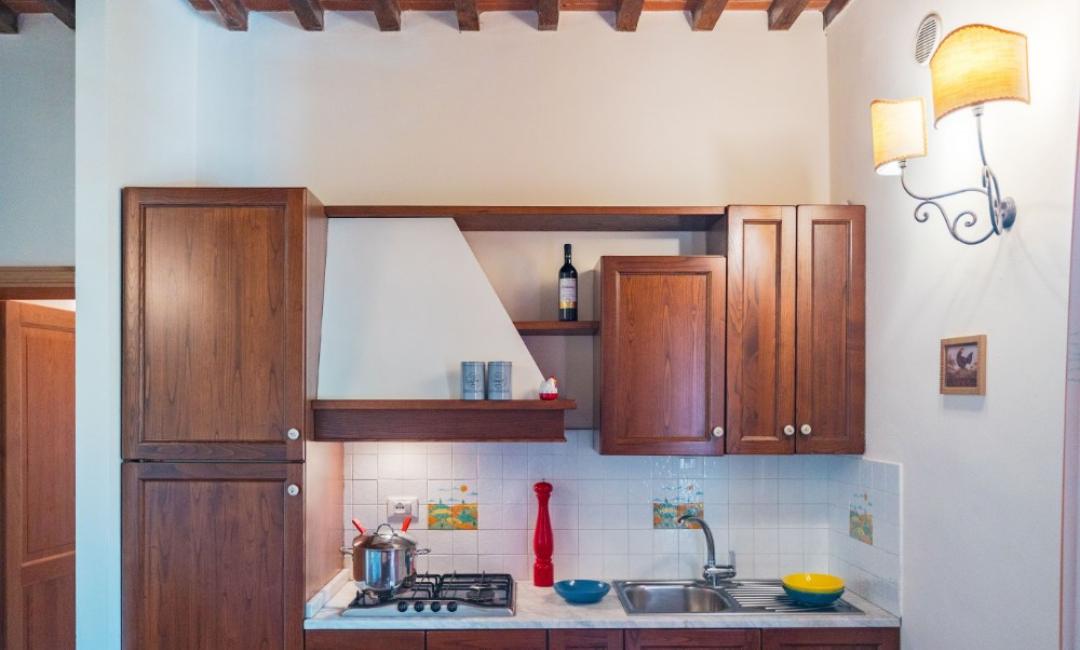 Cuisine avec des armoires en bois, des carreaux blancs et des décorations colorées.