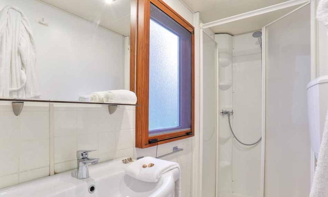 Modernes Badezimmer mit Dusche, Waschbecken und Fenster.