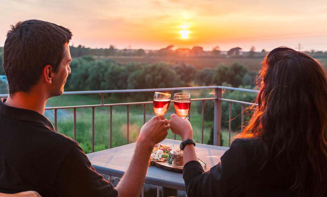 To personer skåler ved solnedgang med glas rosévin.