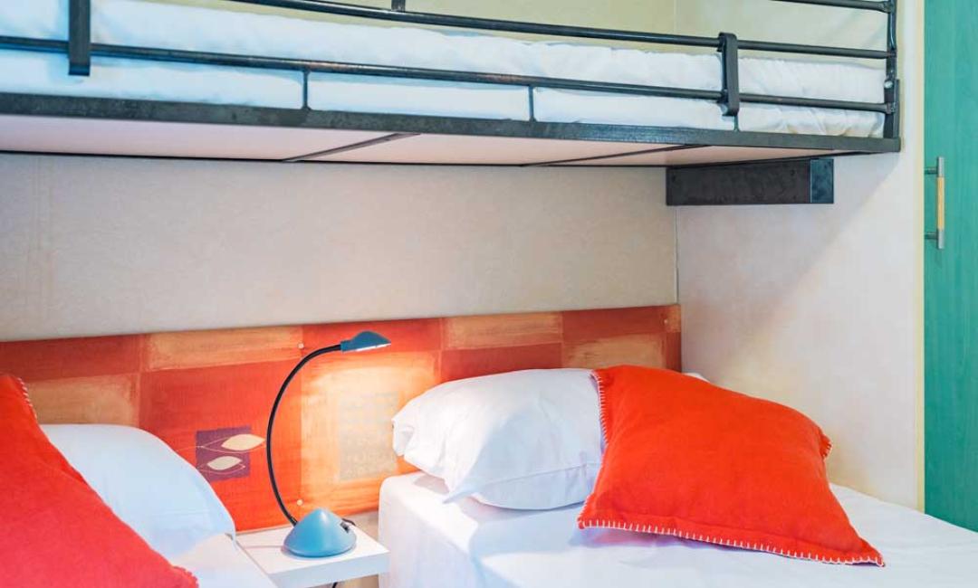 Zimmer mit Etagenbetten und orangefarbenen Kissen.