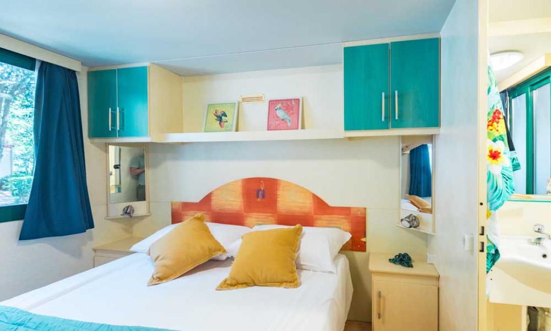 Helles Schlafzimmer mit Doppelbett und bunten Dekorationen.