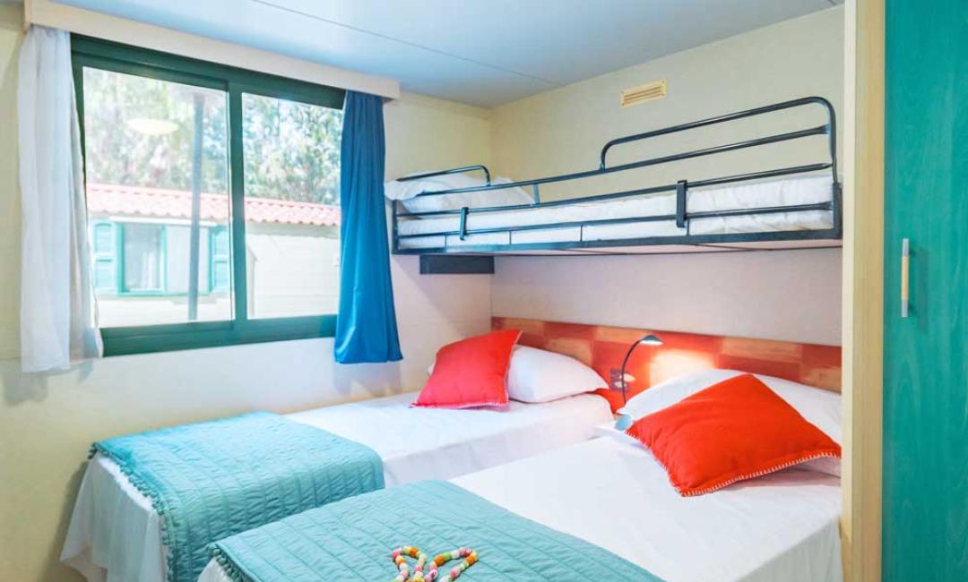 Zimmer mit Einzelbetten und Etagenbett, helles Fenster.