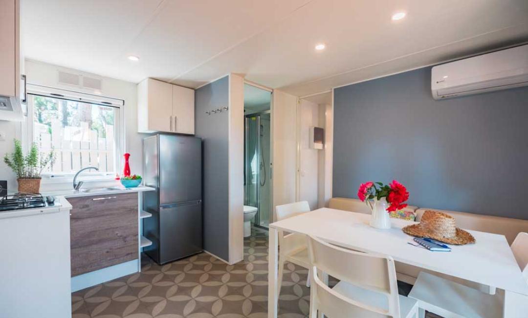 Cuisine moderne avec table à manger et réfrigérateur, décorée de fleurs.