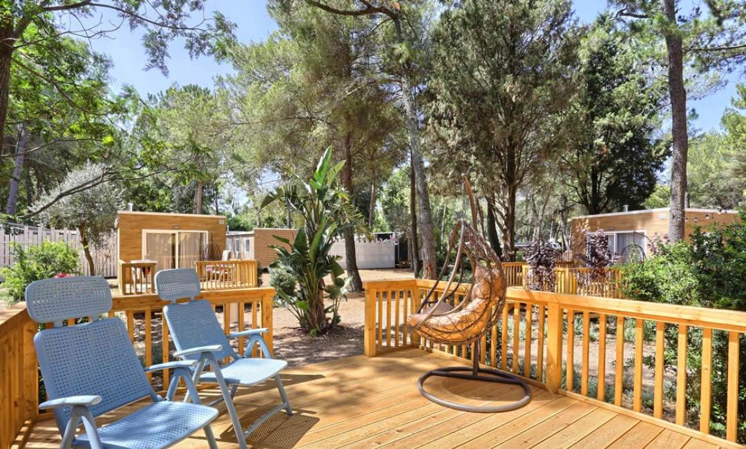 Terrazza in legno con sedie e sedia a dondolo, vista su bungalow.