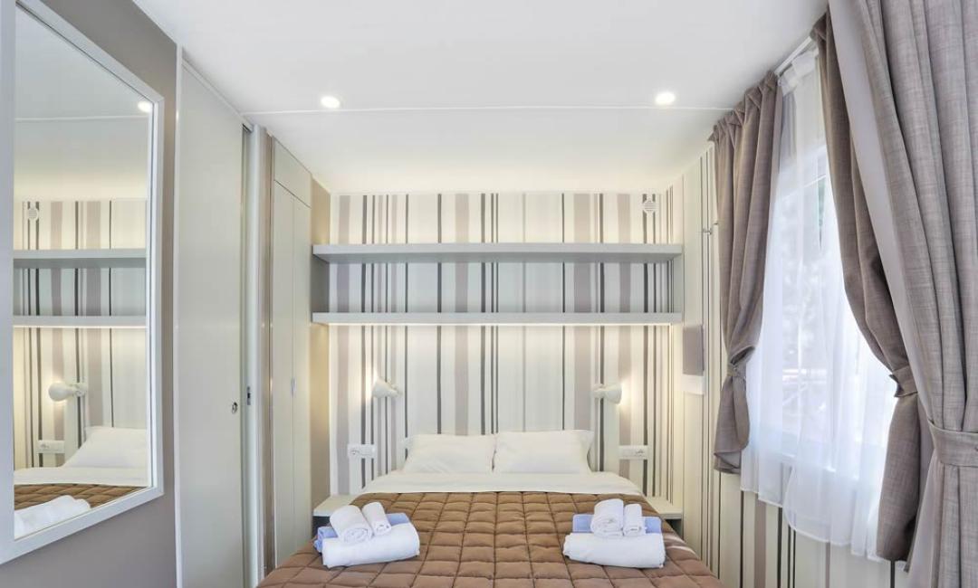 Camera da letto moderna con letto matrimoniale e decorazioni a strisce.
