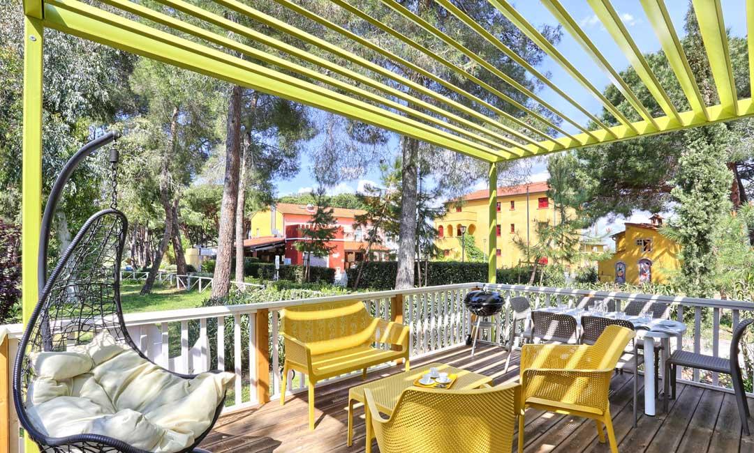 Sunny terrace with yellow chairs, swing, and barbecue.