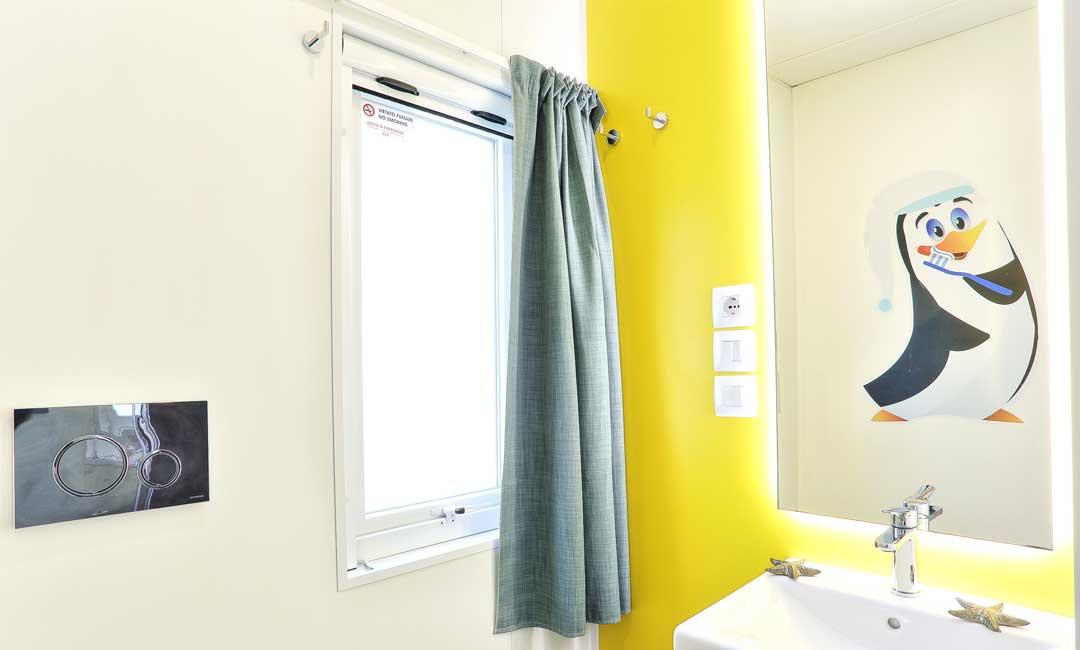 Bathroom with penguin, sink, and window with green curtain.