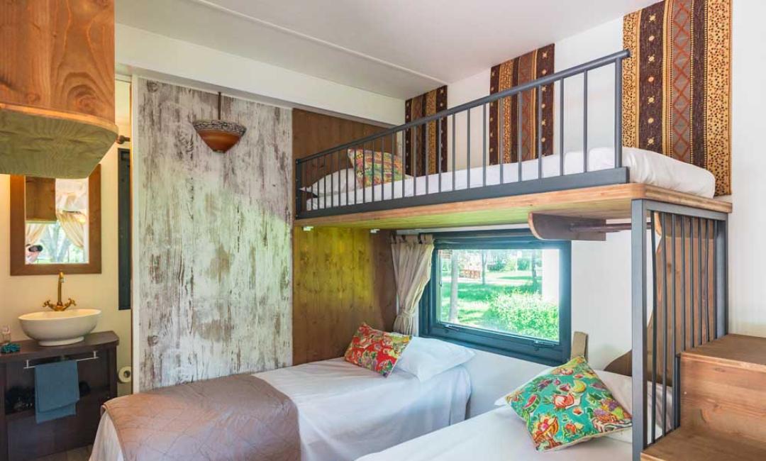 Zimmer mit Etagenbetten, bunte Dekorationen und Gartenblick.