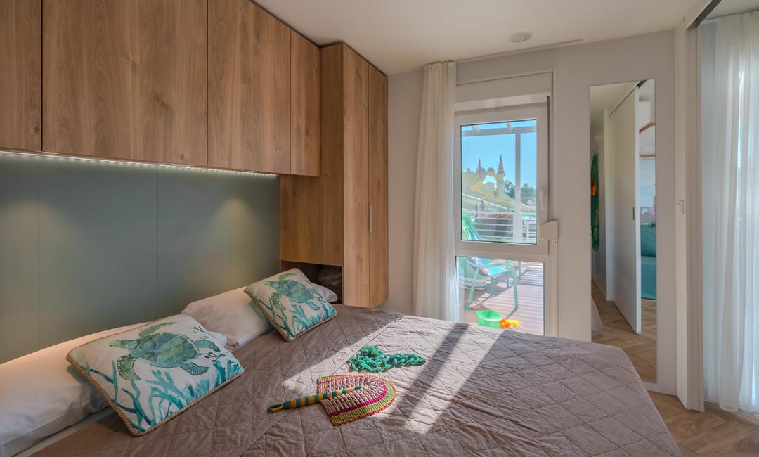 Moderne slaapkamer met houten kasten en balkon uitzicht.
