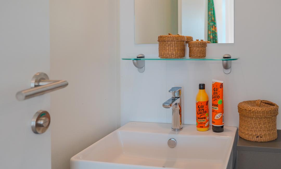 Badkamer met wastafel, spiegel en haarproducten.