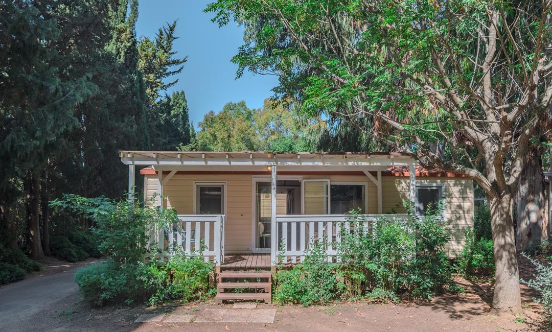 Small house with a porch, surrounded by trees and nature.