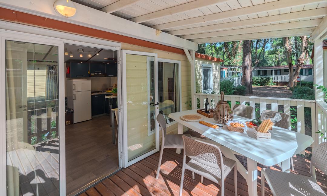 Cozy veranda with dining table, garden view, and modern kitchen.