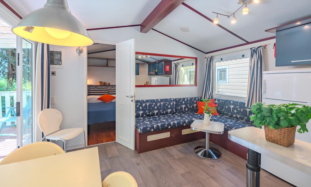 Cozy living room with sofa, kitchen, and view into the bedroom.