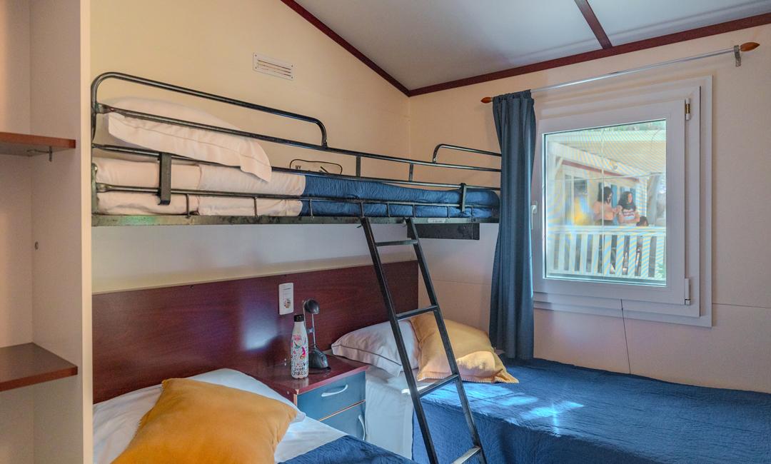 Room with bunk beds, window, and nightstand.