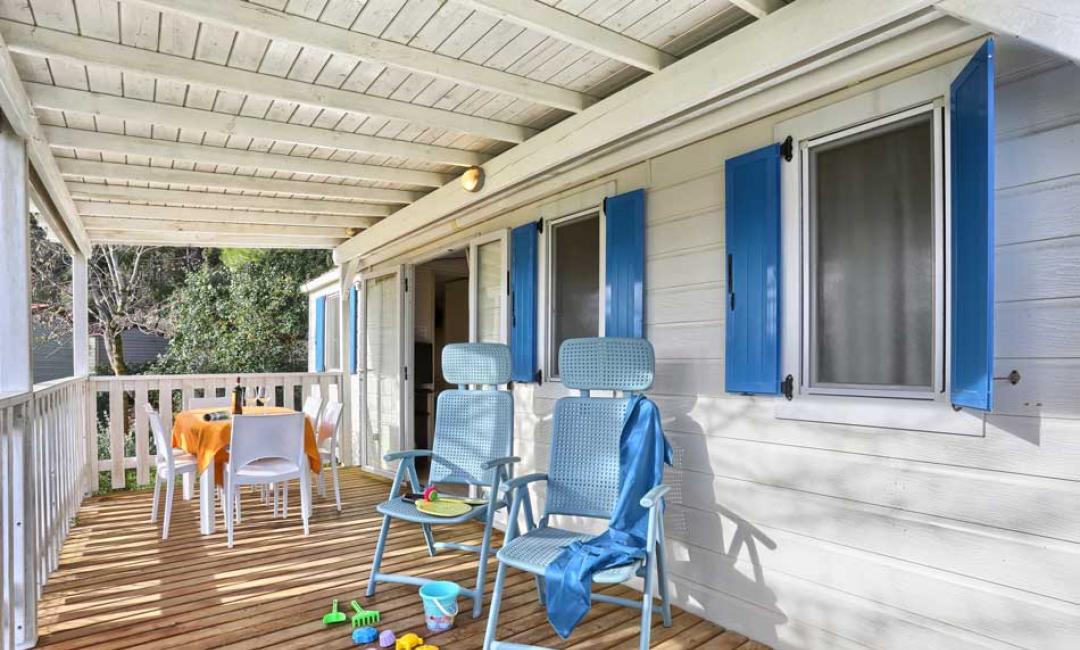 Veranda mit blauen Stühlen, gedecktem Tisch und Kinderspielzeug.