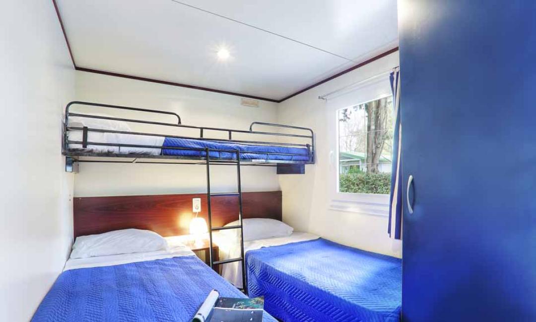 Zimmer mit Etagen- und Einzelbetten, blaue Bettdecken.