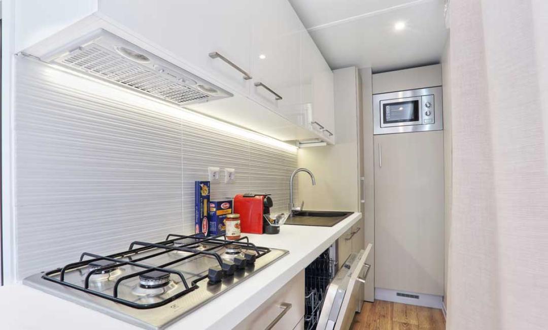 Cuisine moderne avec cuisinière, évier et micro-ondes.