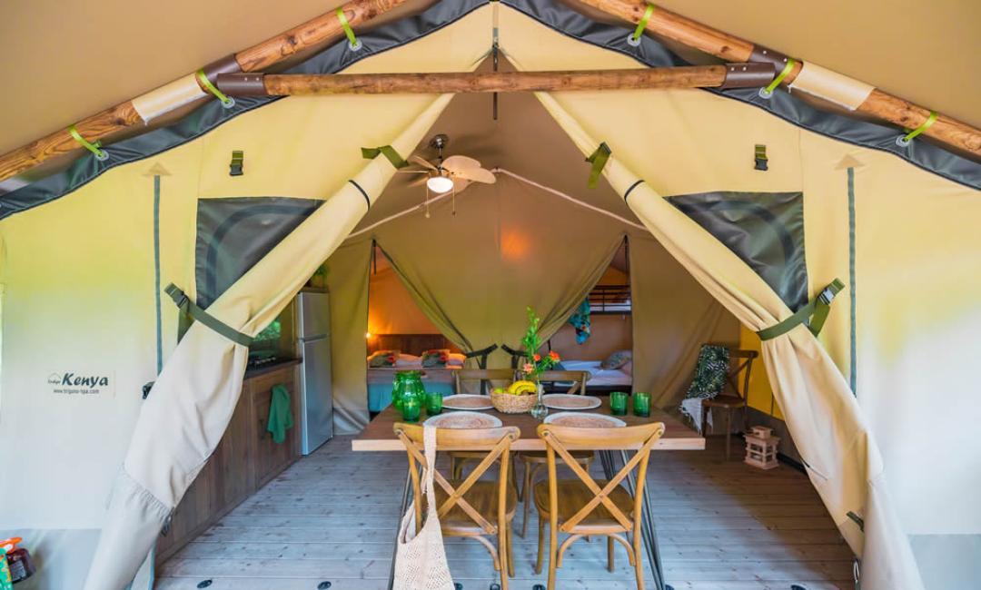 Tente glamping avec cuisine, salle à manger et lits confortables.