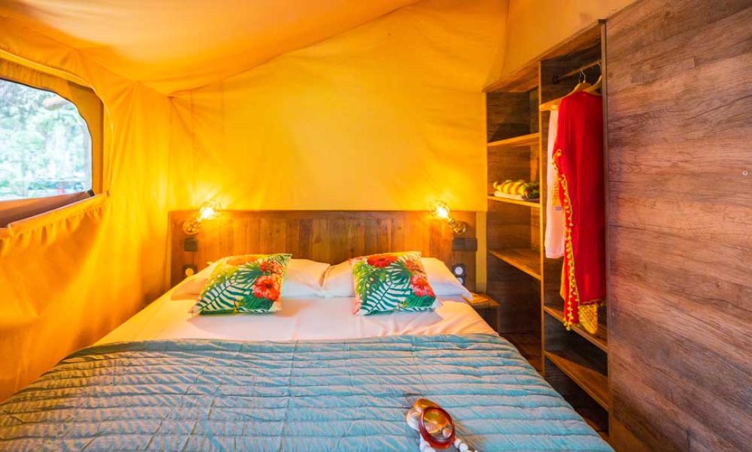 Chambre confortable avec lit double, décorations colorées et armoire ouverte.