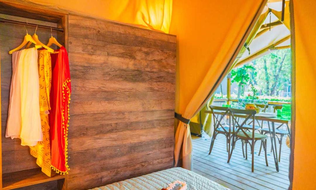 Intérieur d'une tente glamping avec vue sur un espace extérieur aménagé.