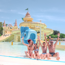 Famiglia felice in un parco acquatico con scivoli e piscina.