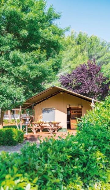 Une cabane en bois entourée de verdure avec des tables de pique-nique à l'extérieur.