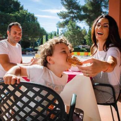 Happy family sharing a meal outdoors on a sunny day.